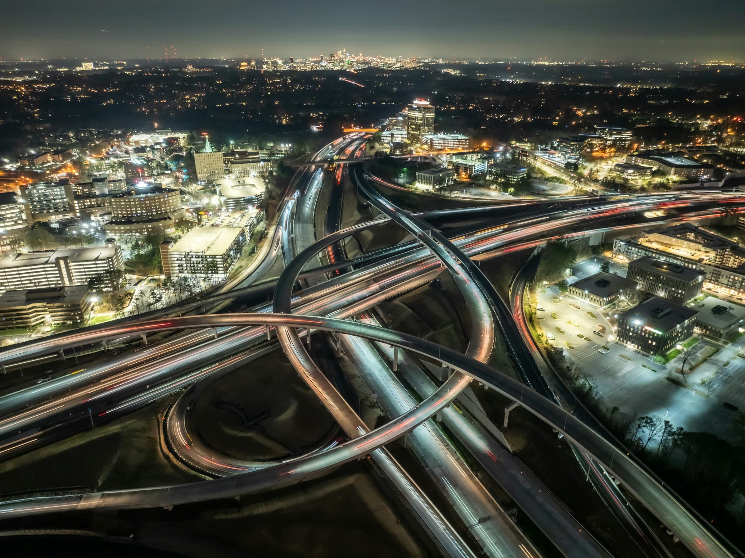 Aerial view of a major highway interchange and city infrastructure at night